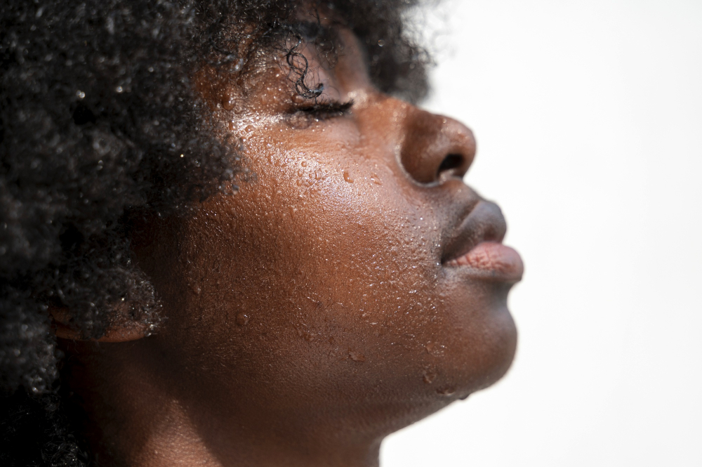 Black woman gently cleansing her face with water